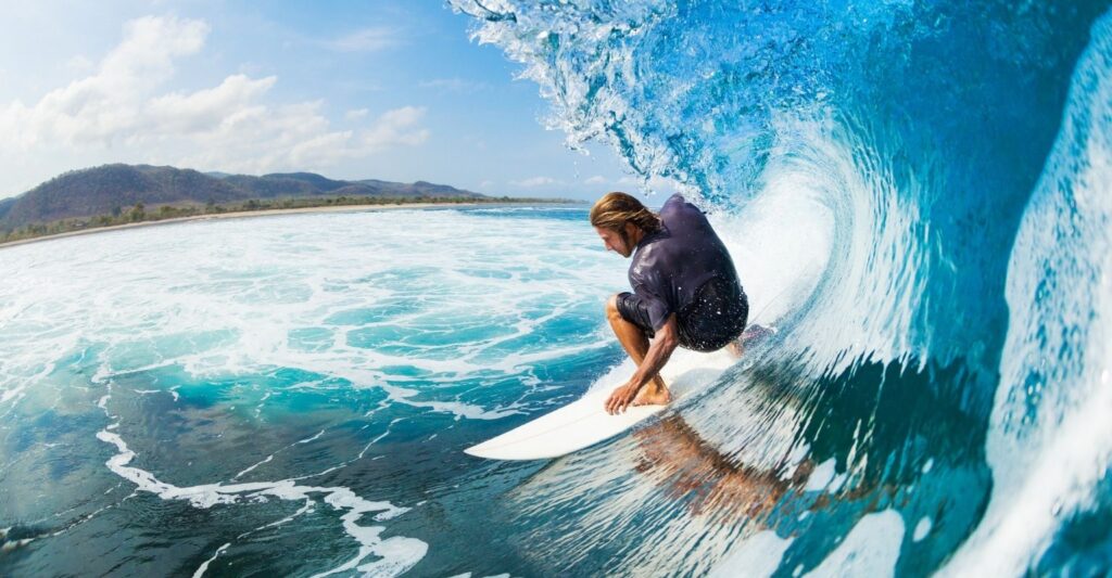 man on surfboard surfing big wave wearing custom surfplugs