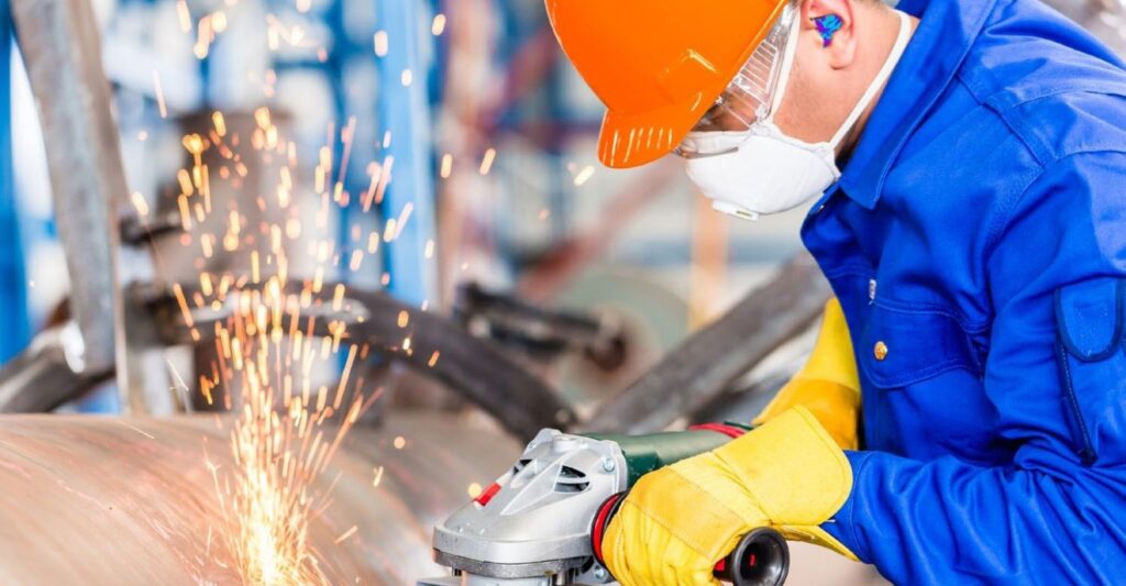 Man on grinder wearing orange hat with yellow gloves