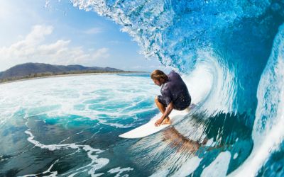 man on surf board surfing wearing custom earplugs for surfing